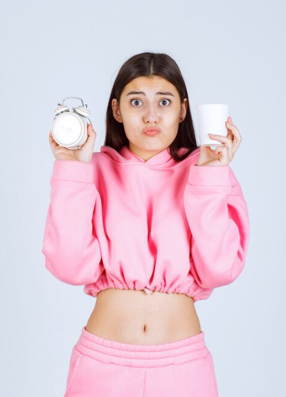 Femme qui porte une horloge et un café dans chacun de ses mains 
